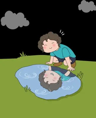 Boy kneeling at the edge of a puddle looking at his own reflection