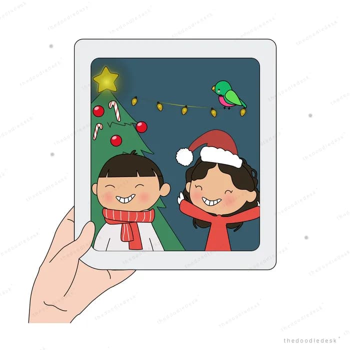 Hand holding a tablet showing two children in santa hats by a christmas tree