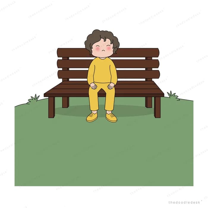 Boy in yellow sitting alone on a park bench looking downcast