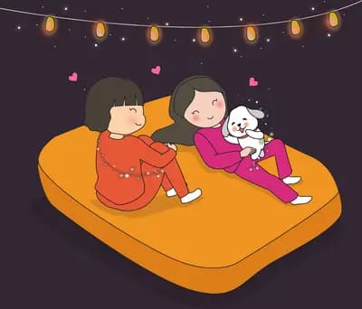 Two girls lying on an orange mattress with a cat under a string of lanterns
