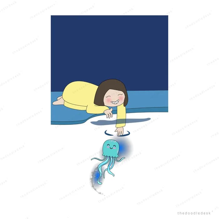 Girl lying on a dark ledge reaching down toward a glowing jellyfish in the water