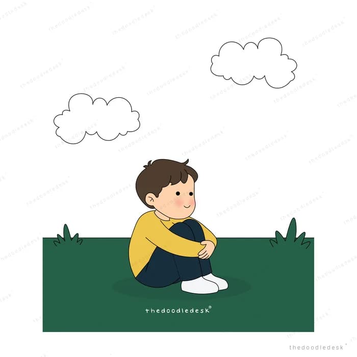 Boy hugging his knees on a green field under two white clouds